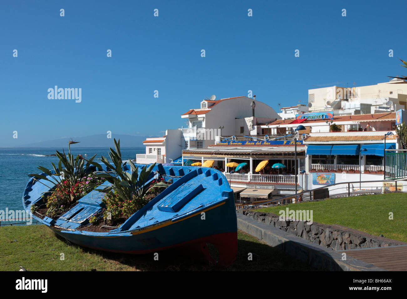 Una vecchia barca da pesca si arricchisce di una nuova vita come un vaso di fiori su un prato dai ristoranti di La Caleta sulla costa occidentale di Tenerife Foto Stock