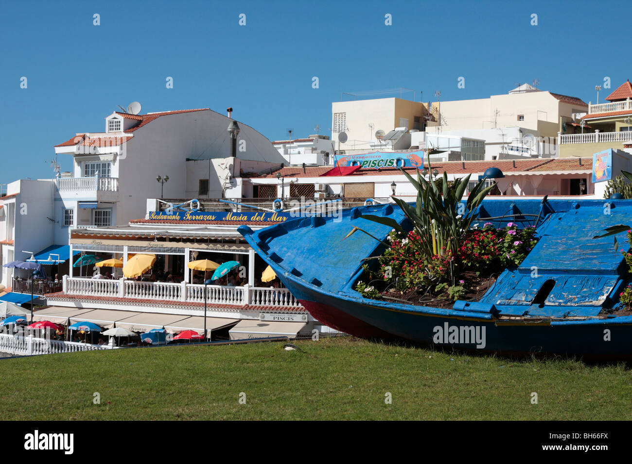 Una vecchia barca da pesca si arricchisce di una nuova vita come un vaso di fiori su un prato dai ristoranti di La Caleta sulla costa occidentale di Tenerife Foto Stock