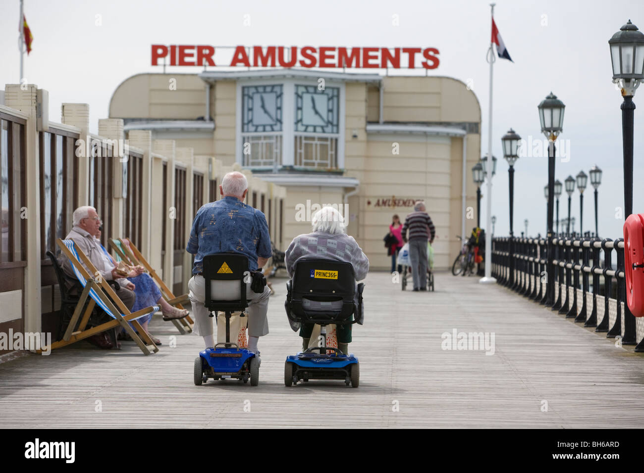 Pentioners sulla mobilità scooter guidare lungo Eastbourne Pier. Foto di James Boardman Foto Stock