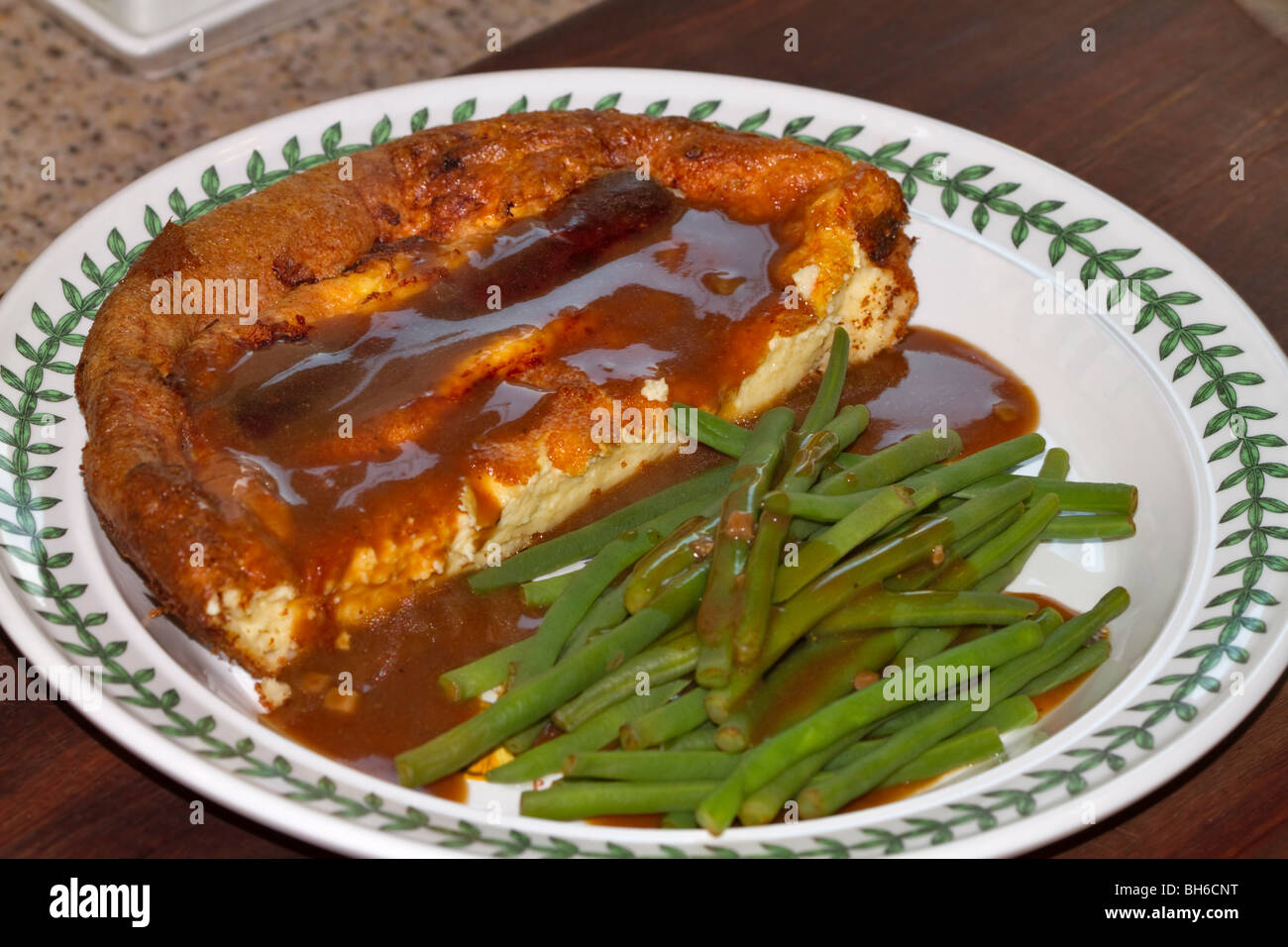 Toad nel foro, britannica tradizionale piatto di salsiccia in Yorkshire pudding con fagiolini freschi e sugo di carne Foto Stock