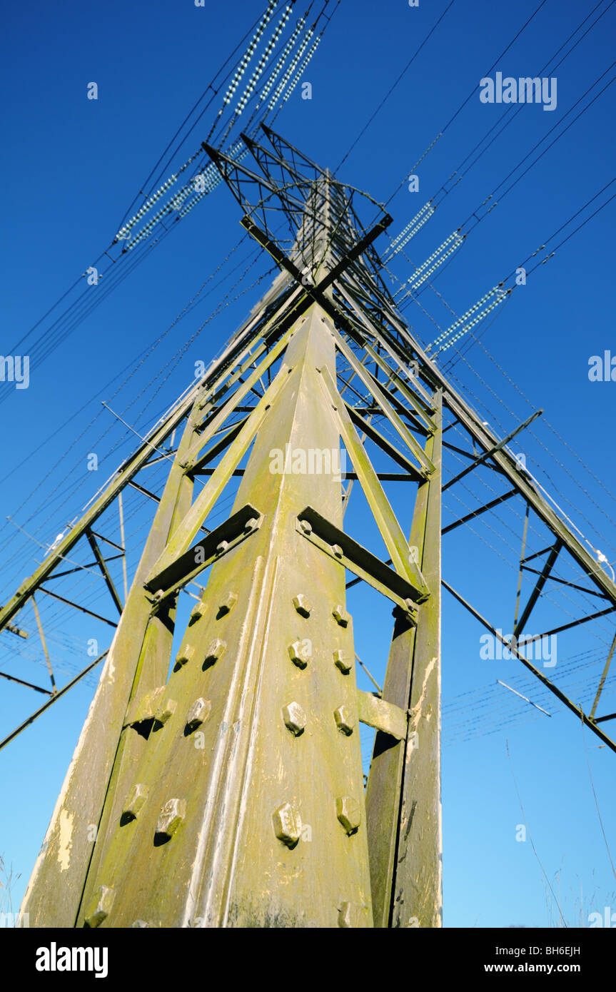 Elettricità pilone vista verso l'alto da un insolito angolo alla base di un supporto con cielo blu chiaro dietro Foto Stock