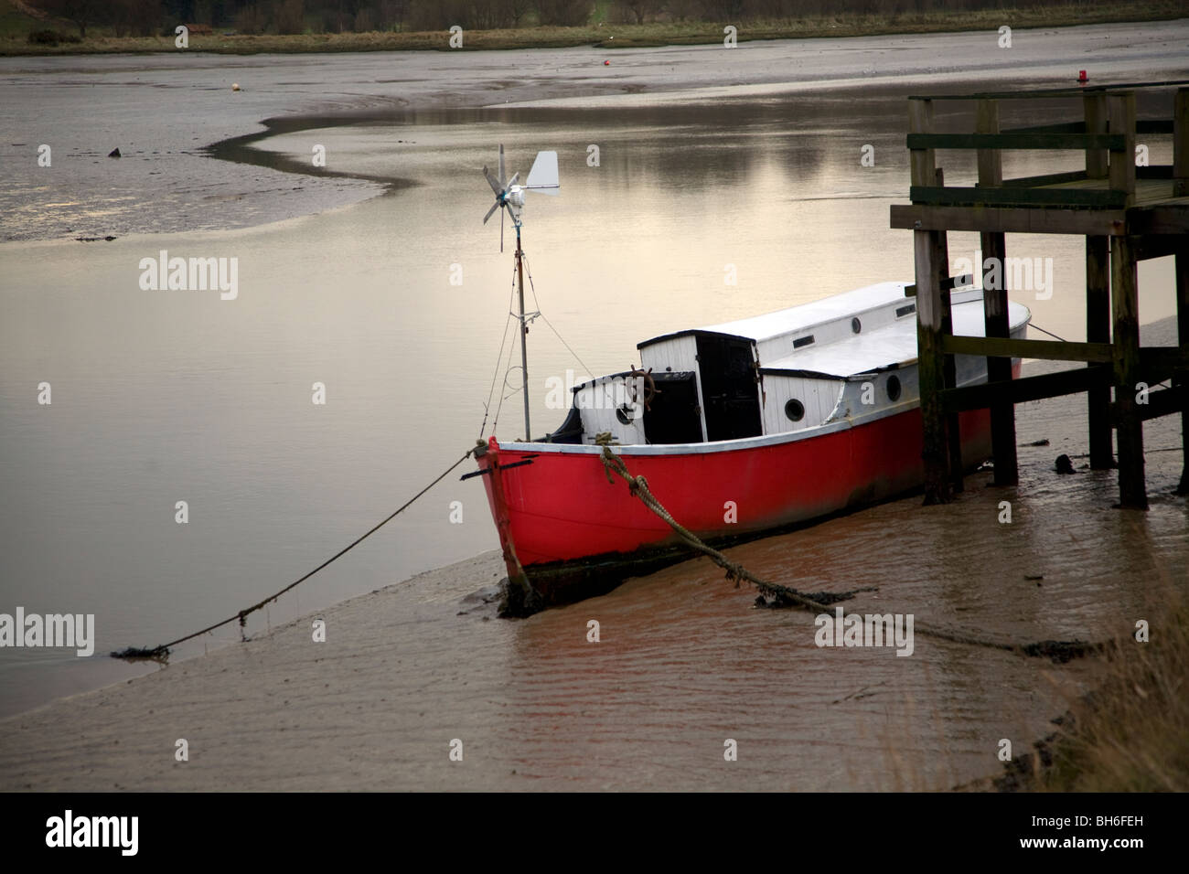 Imbarcazione con carena rosso ormeggiata in fango sul fiume Deben, Melton, Suffolk, Inghilterra Foto Stock