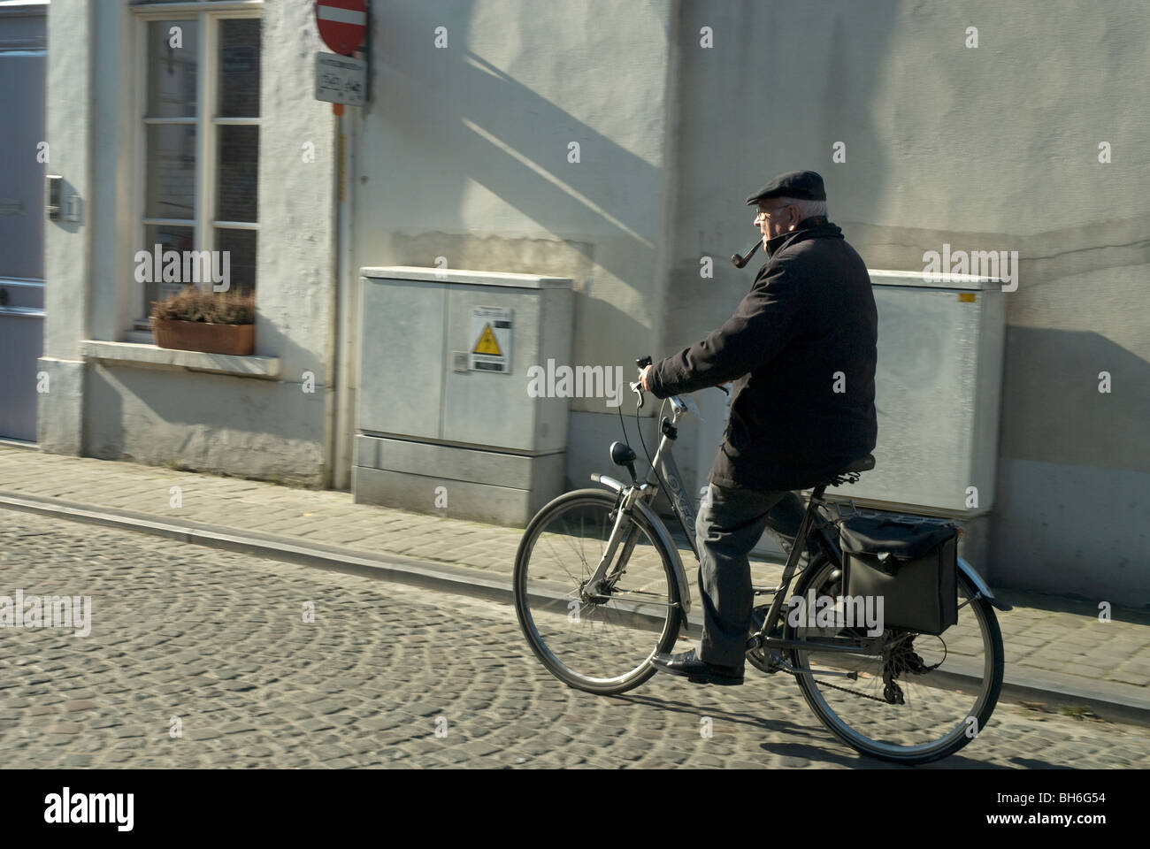 Ciclista solitario di fumare una tubazione, Brugge, Fiandre Occidentali, Belgio Foto Stock