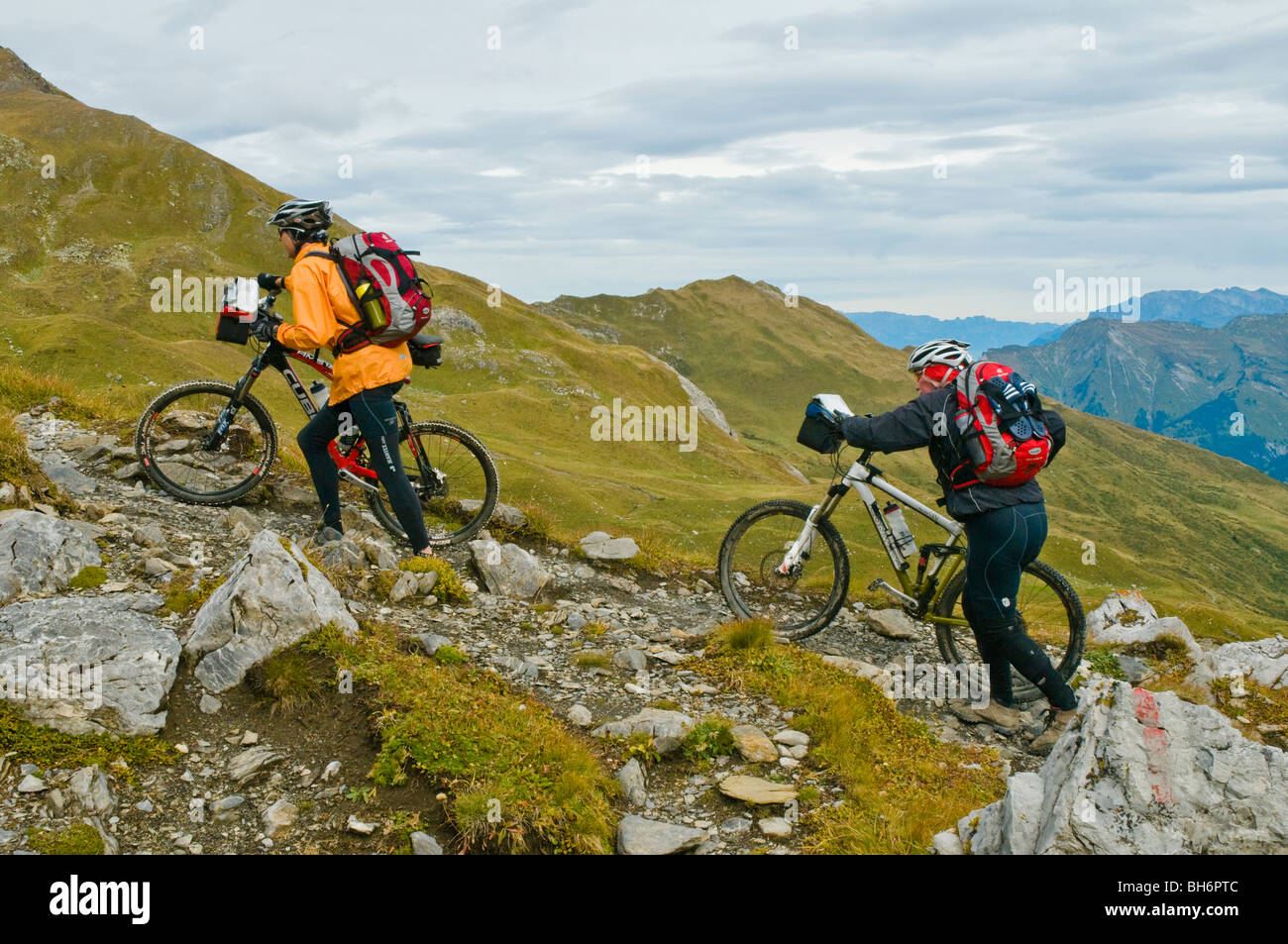 Due mountain bikers spingere in salita il sentiero di Grischa vicino Hornli tra Arosa e Lenzerheide, Grigioni, Svizzera Foto Stock
