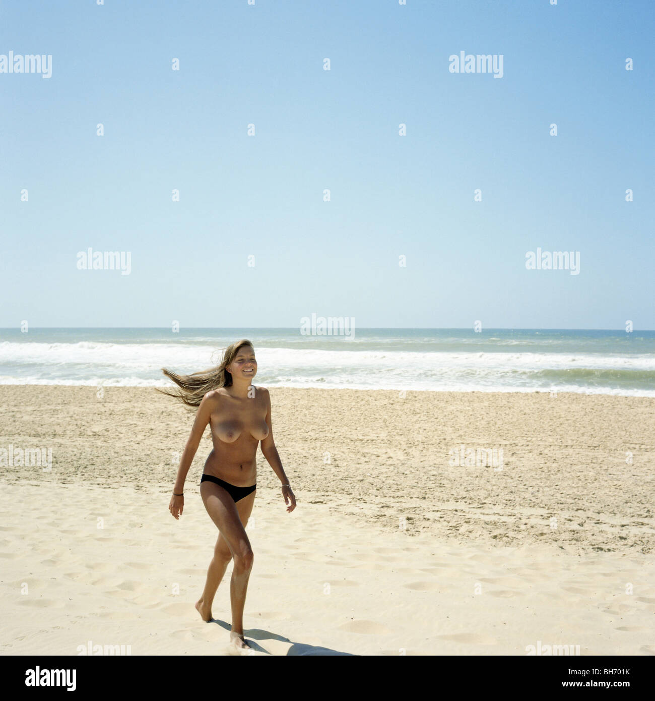In topless di donna camminando sulla spiaggia vuota Foto stock - Alamy