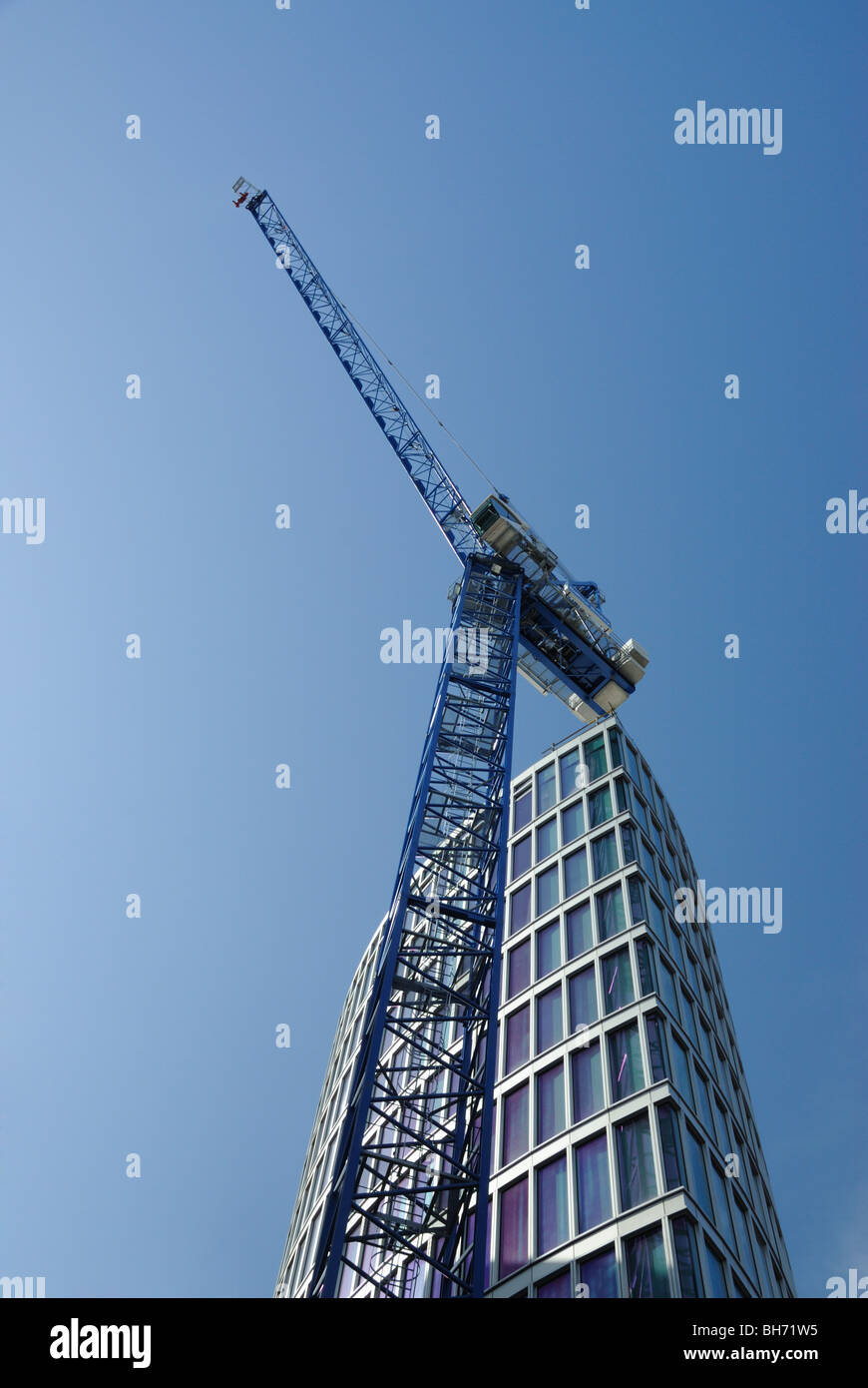 Gru da cantiere in luminoso soleggiato con alto edificio dietro Foto Stock