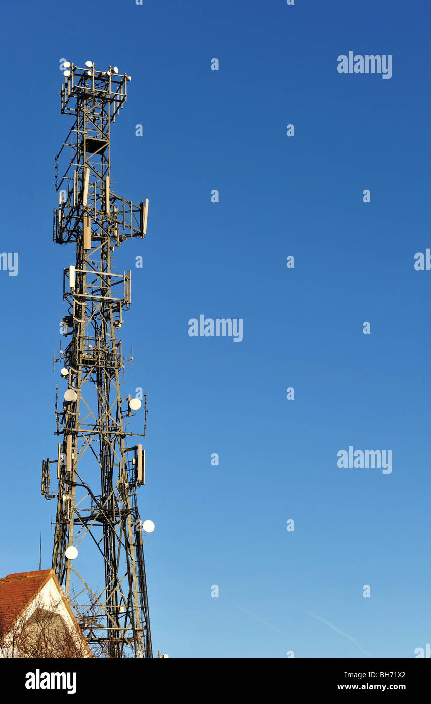 Telefono cellulare e la torre delle comunicazioni adottate contro un cielo blu chiaro. Foto Stock