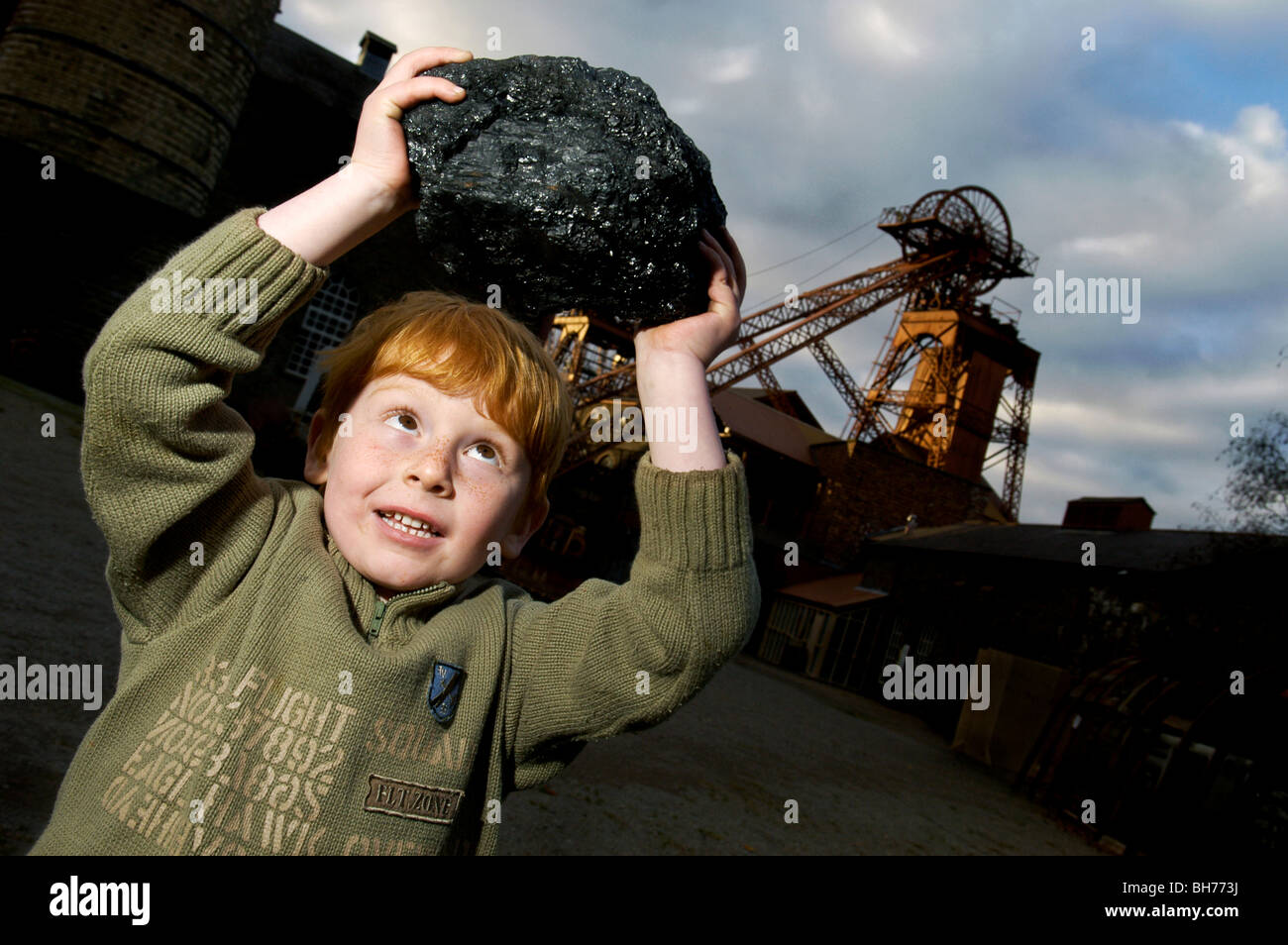 Un piccolo ragazzo solleva uno degli ultimi pezzi di carbone con la Rhondda Heritage Park nella Rhondda Valley, nel Galles del Sud. Foto Stock