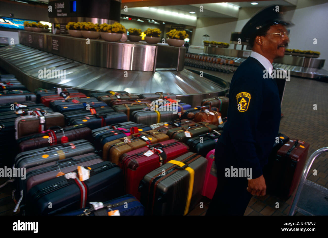 Una guardia di sicurezza si erge su bagagli lasciati incustoditi all'Aeroporto Hartsfield di Atlanta la sala arrivi giostra. Foto Stock