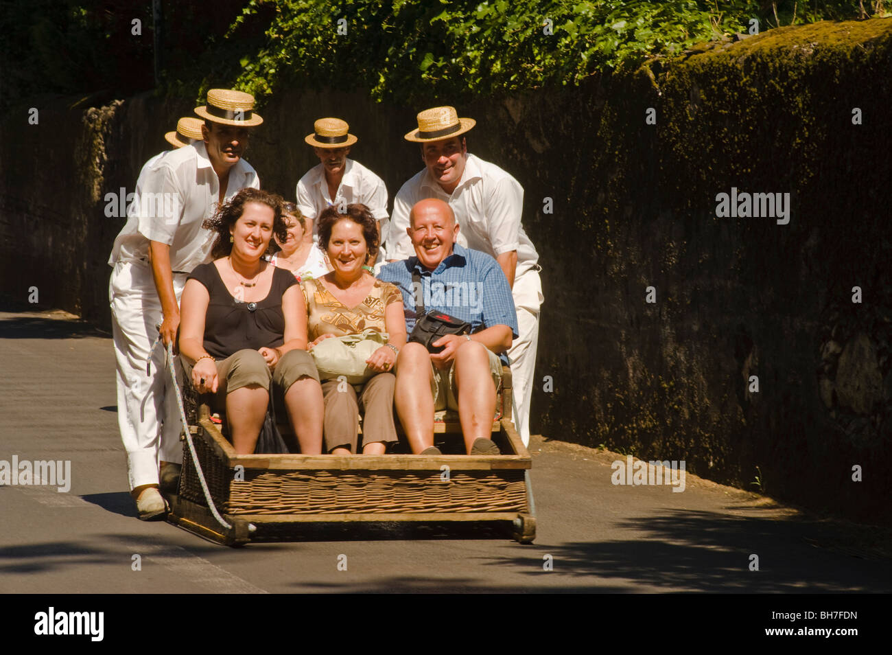 I turisti scendono ripide stradine di monte in un tradizionale tobogan, Funchal, Madeira Foto Stock