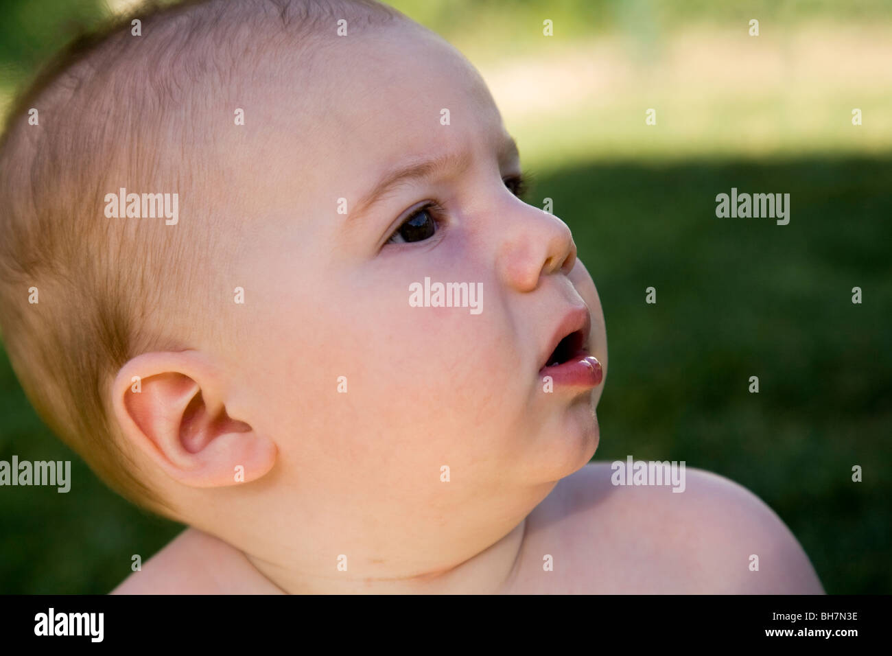 Perplesso diciotto mesi baby boy in giardino Foto Stock