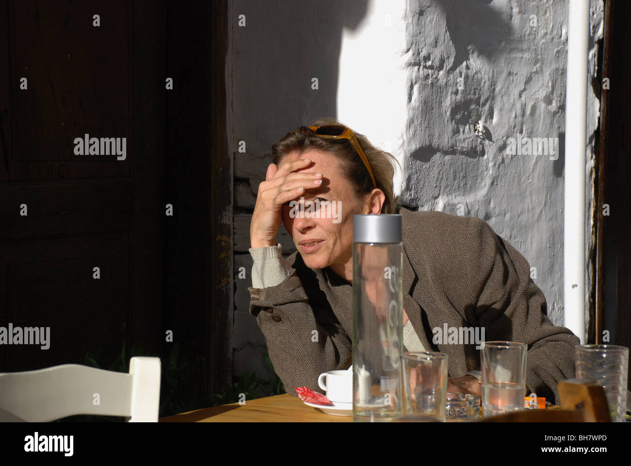 Donna strizzare gli occhi alla luce del sole con ombreggiatura a mano i suoi occhi Foto Stock