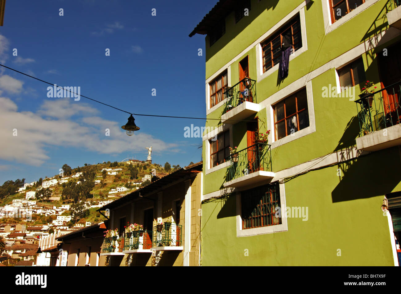Equador, Quito Quito la Madonna a basso angolo di visione di un dipinto di verde struttura residenziale con la gente che camminava sul marciapiede Foto Stock