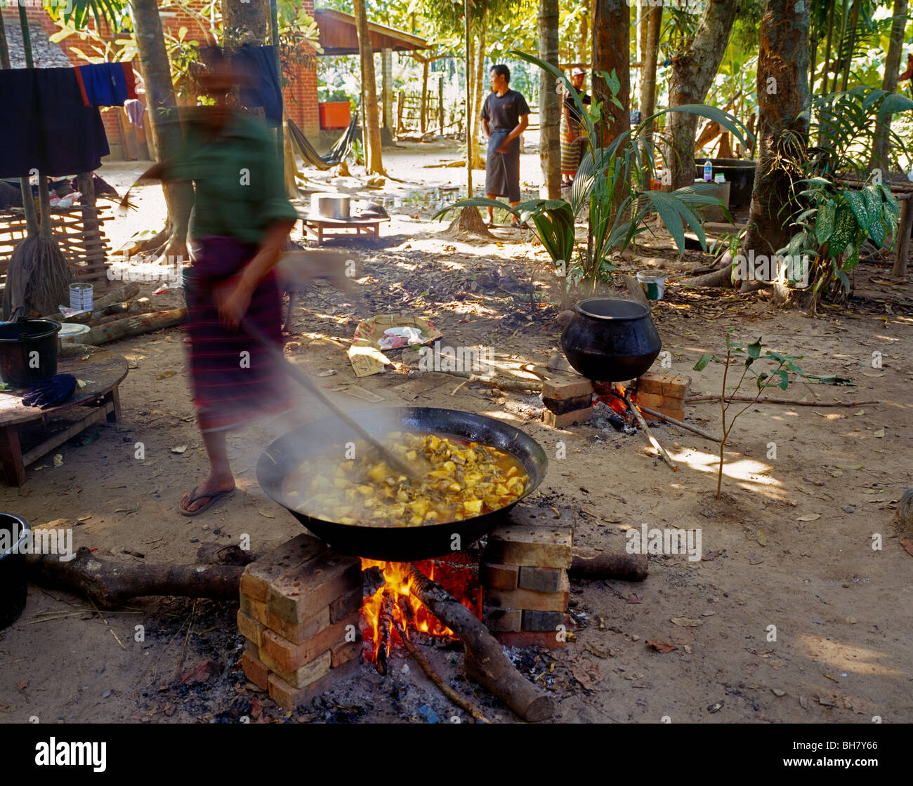 Uomo di cottura degli alimenti in un wok ampio per un villaggio di festa Essen wird für ein Dorffest zubereitet Kayin membro MYANMAR Birmania Foto Stock