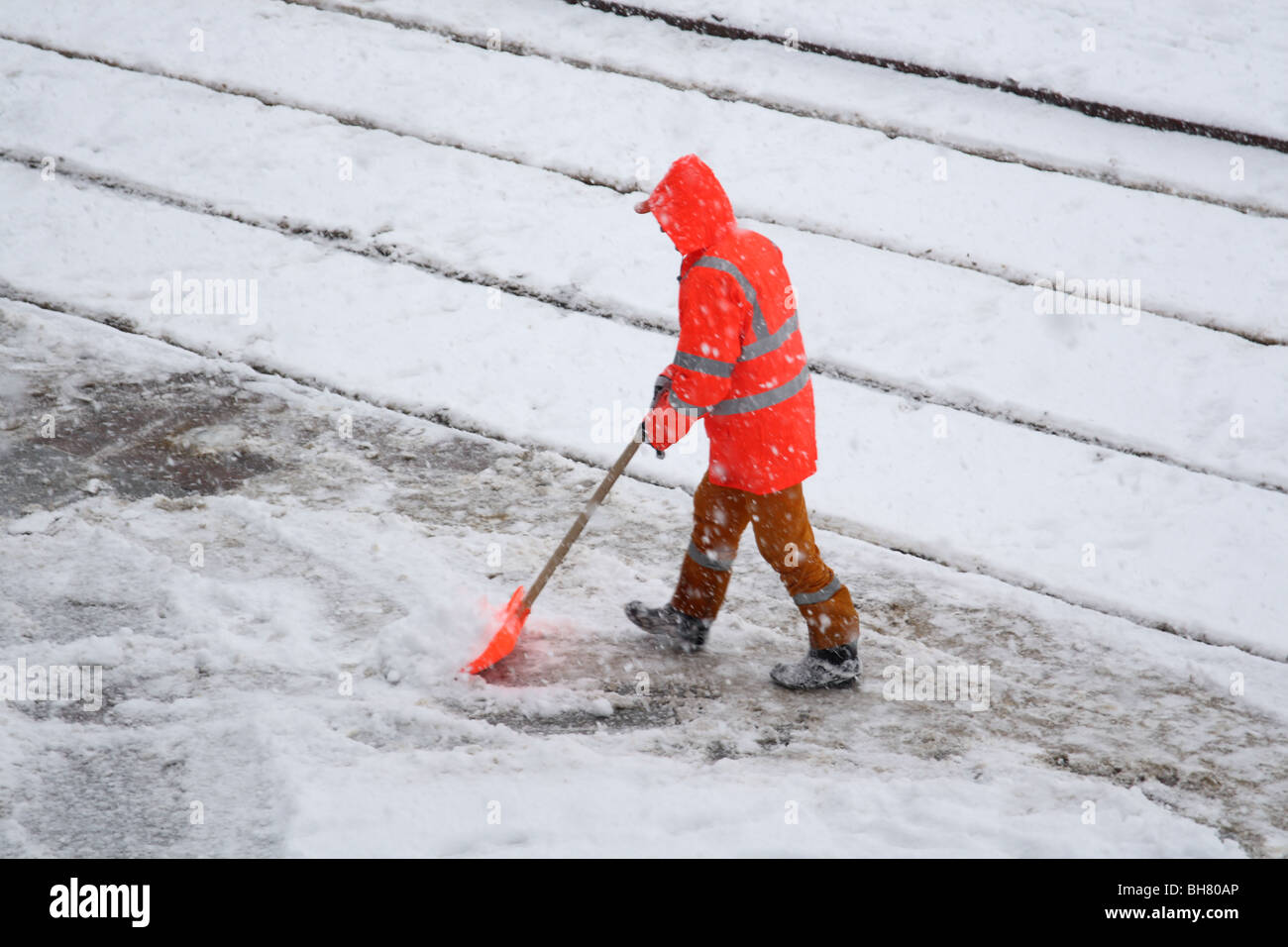 Un uomo spalare la neve durante la nevicata Foto Stock