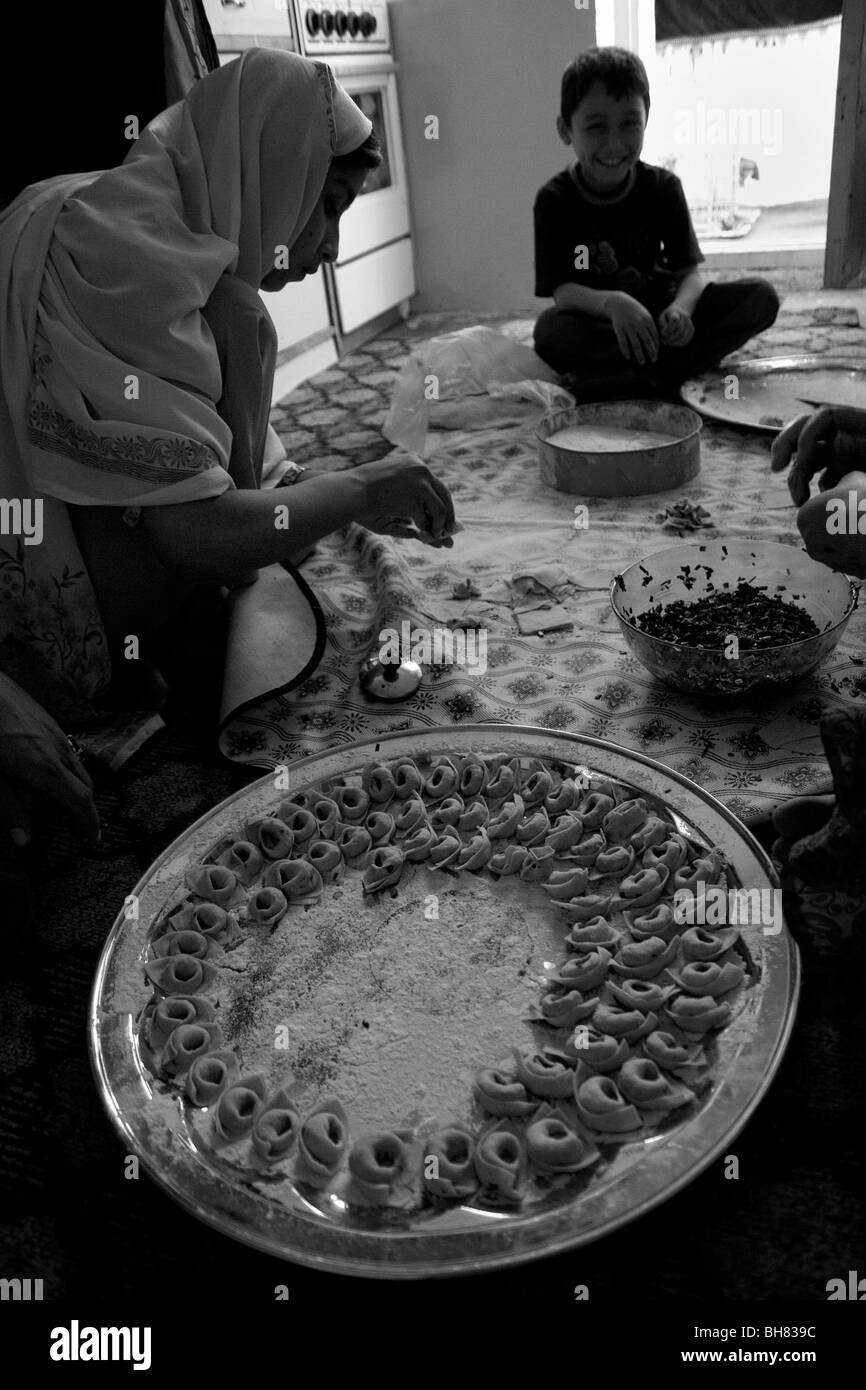 Famiglia locale sedersi sul pavimento della cucina e la produzione di pasta riempita con il porro per un piatto chiamato Aash a Kabul in Afghanistan Foto Stock