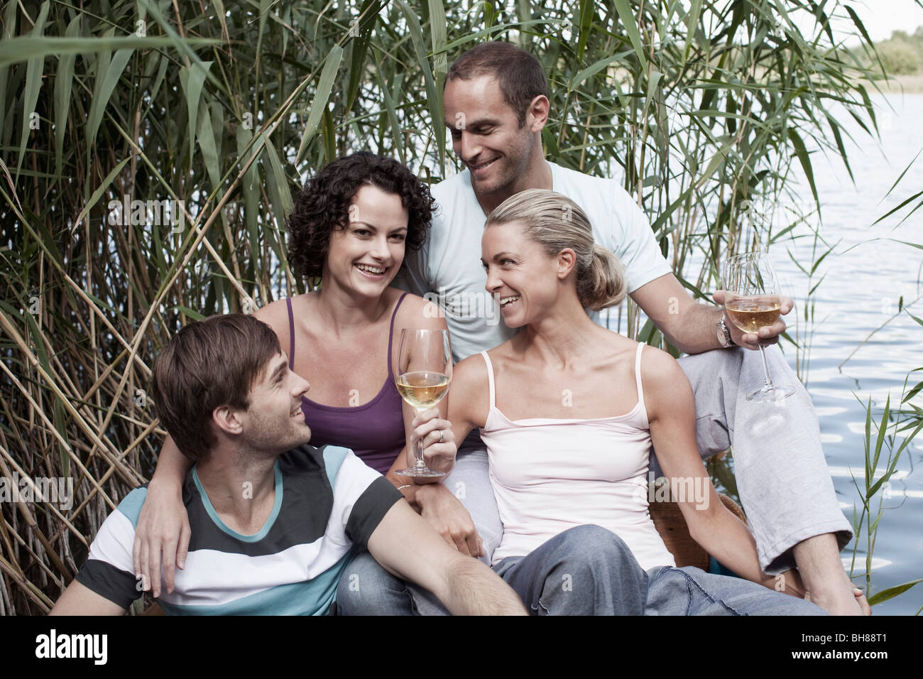 Quattro amici seduti vicino a un lago Foto Stock