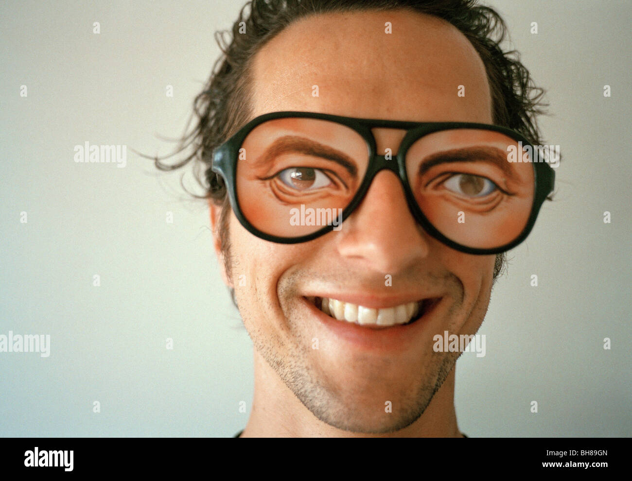 Un uomo che indossa gli occhiali di novità e sorridente Foto Stock