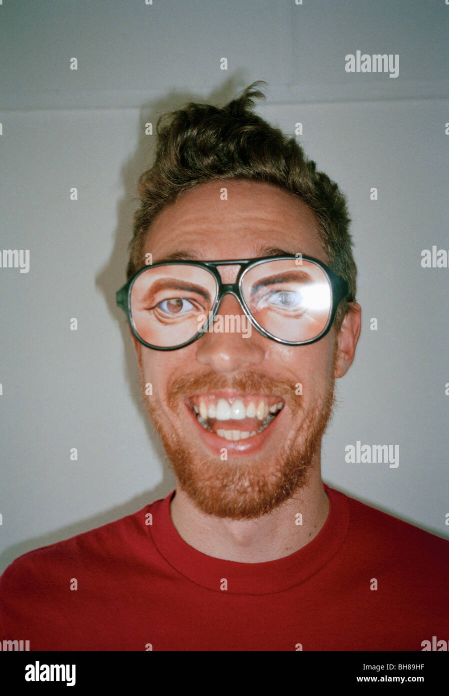 Un uomo che indossa gli occhiali di novità e sorridente Foto Stock