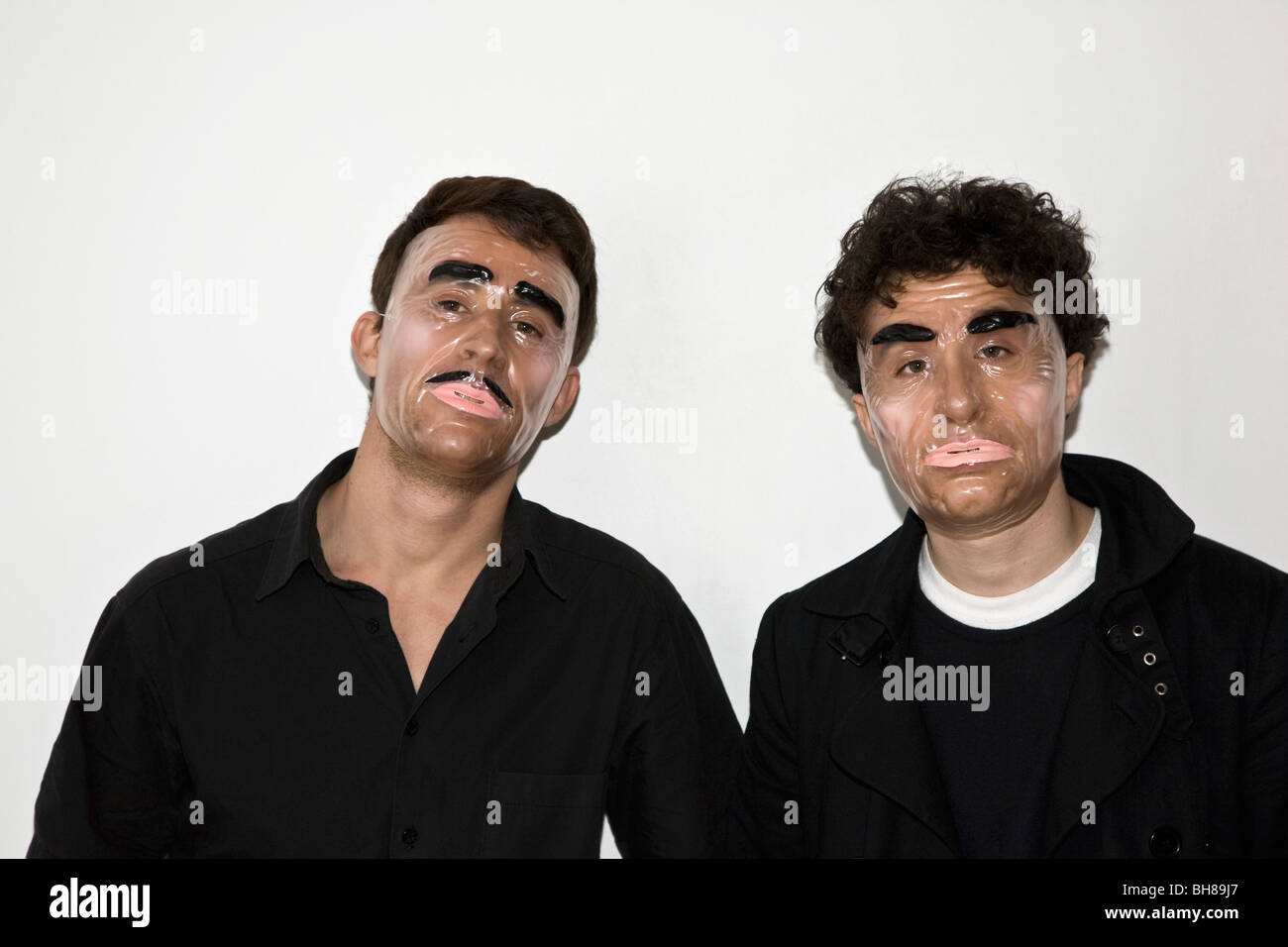 Due uomini in posa di maschere di novità Foto Stock