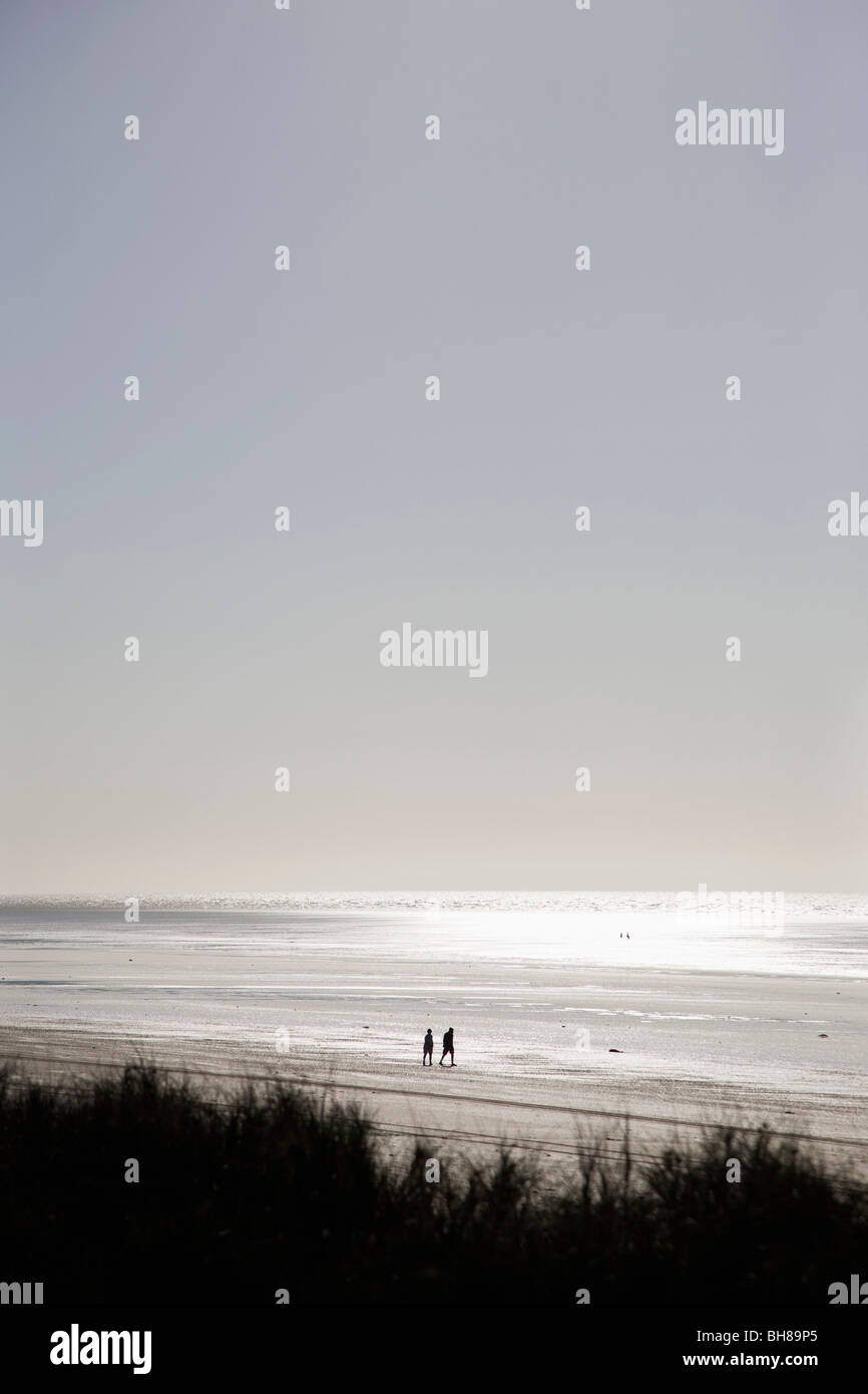 Una vista di due persone di camminare sulla spiaggia Foto Stock