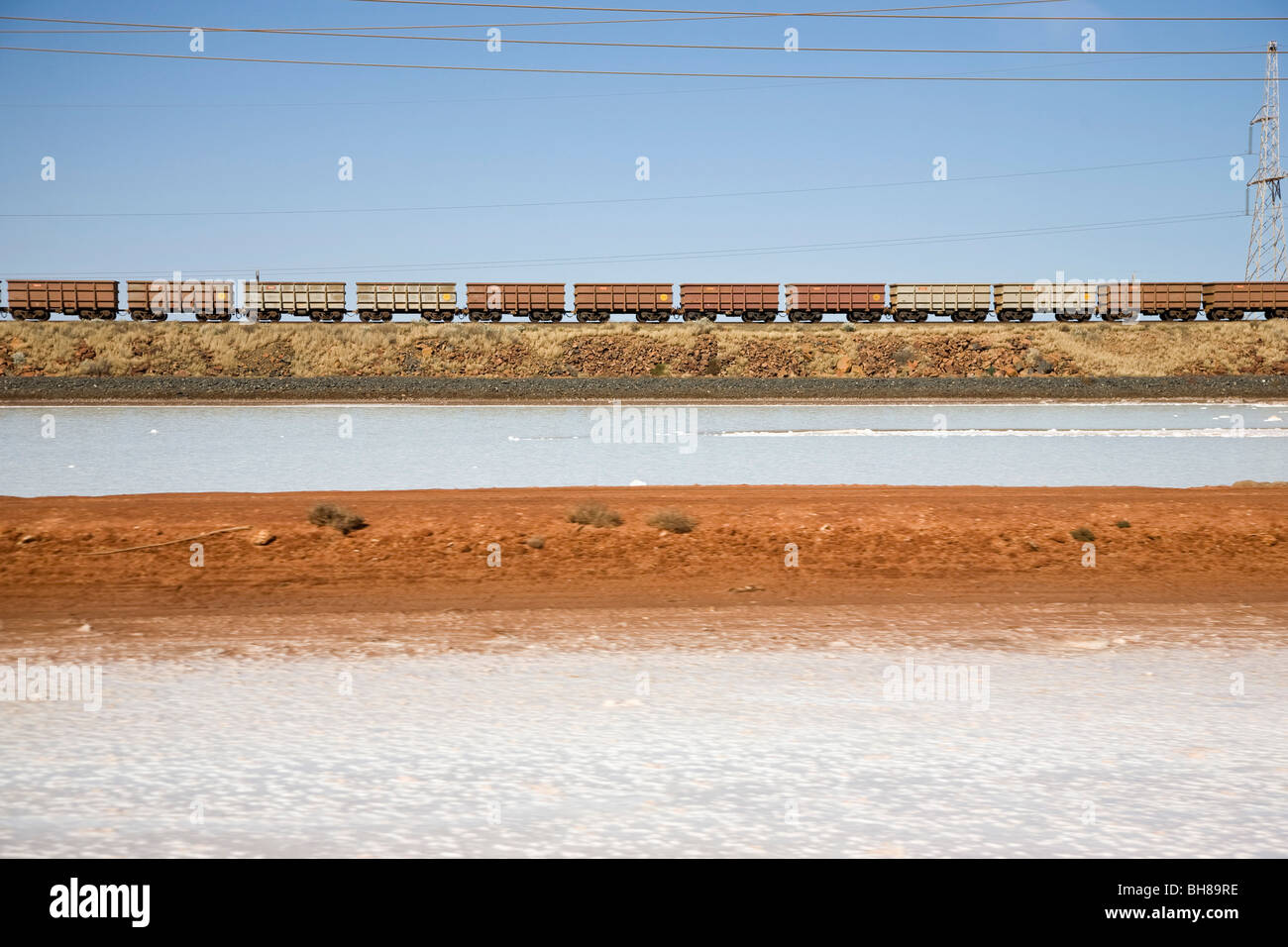 Treno merci che si muove attraverso un paesaggio arido Foto Stock