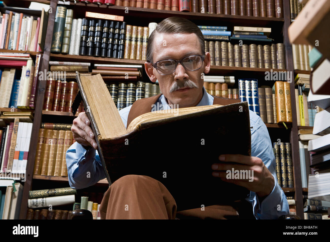 Un uomo che legge un libro in una libreria Foto Stock