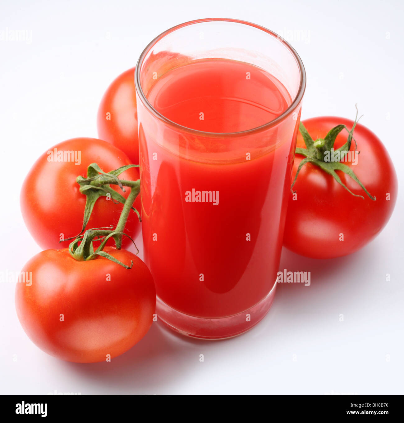 Bicchiere di succo di pomodoro e i pomodori maturi isolato su bianco Foto Stock
