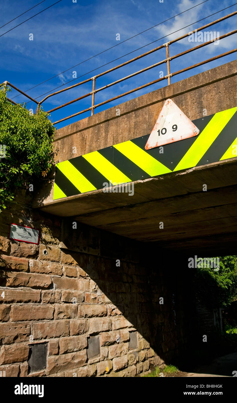 Bassa ponte ferroviario con cartelli di avvertimento per i conducenti di veicoli alti in Cumbria Inghilterra REGNO UNITO Foto Stock