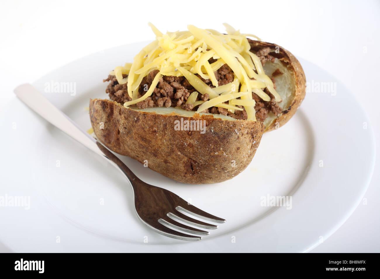 Una camicia o patate al forno e rabboccato con carne macinata e formaggio,  con una forcella su una piastra bianca Foto stock - Alamy