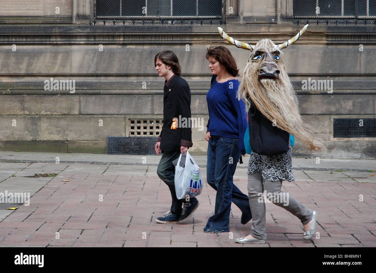 Tre persone che camminano in Edimburgo, una portante un GNU (?) maschera!! Foto Stock