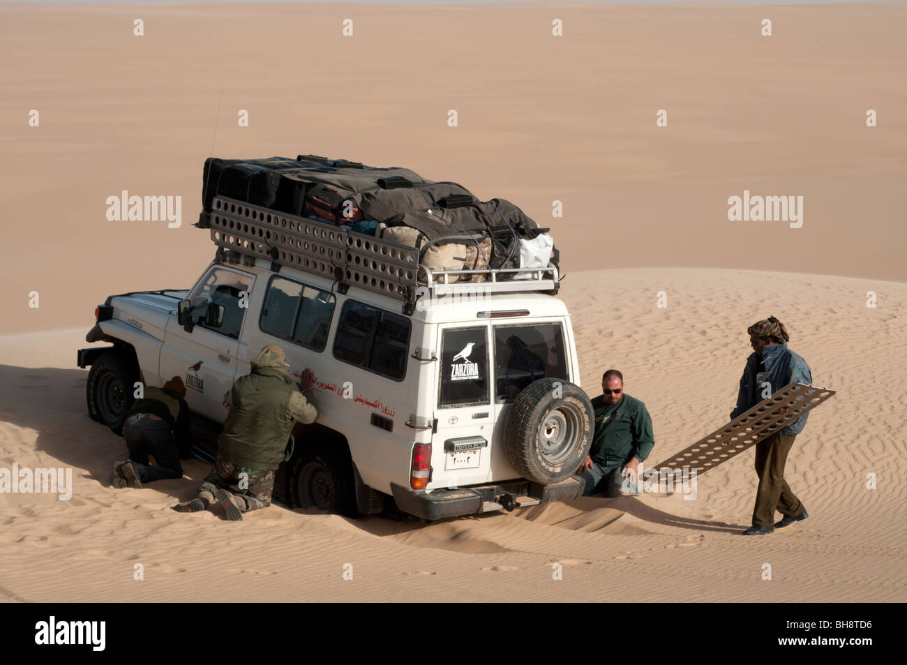 Un safari nel deserto land cruiser jeep 4x4 si blocca in una patch di soffice sabbia nel grande mare di sabbia del deserto occidentale, Sahara egiziano, Egitto. Foto Stock