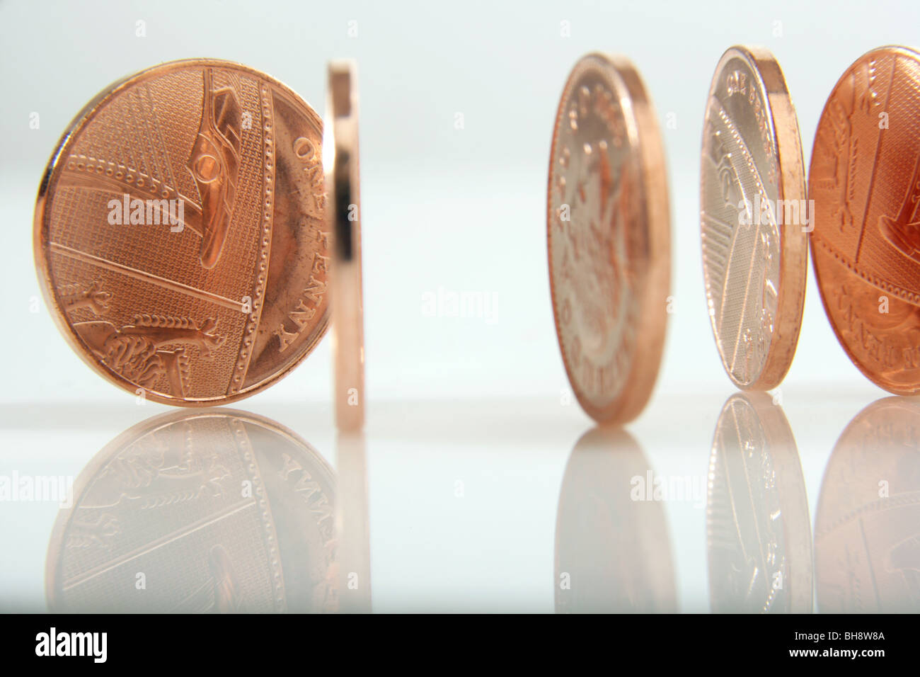 British penny monete in piedi sui loro bordi su uno sfondo bianco. Foto Stock