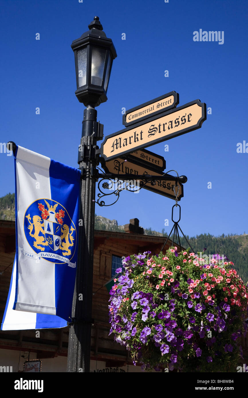 Indicazioni stradali su una lampada posta con bandiera bavarese in Leavenworth una località bavarese di città in Chelan County, Washington, Stati Uniti Foto Stock