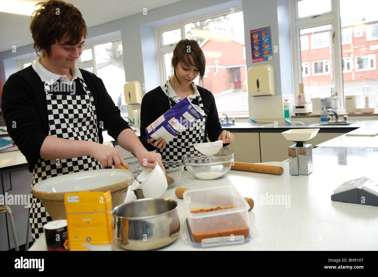 Due adolescenti gli allievi - un ragazzo e una ragazza la misurazione degli ingredienti in scienze alimentari classe di cucina , scuola secondaria REGNO UNITO Foto Stock