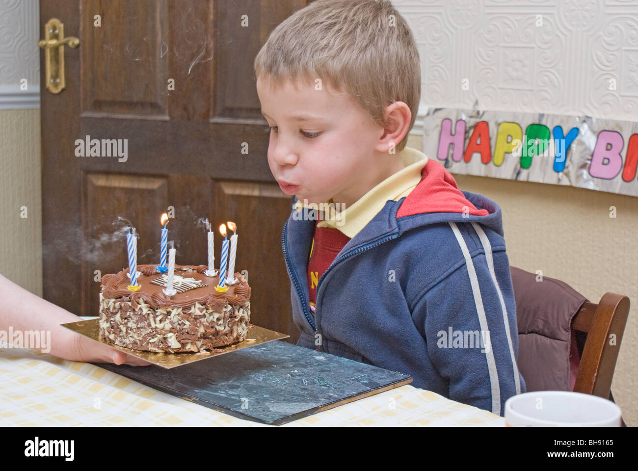 Il ragazzo si brucia candele sulla sua torta di compleanno Foto Stock