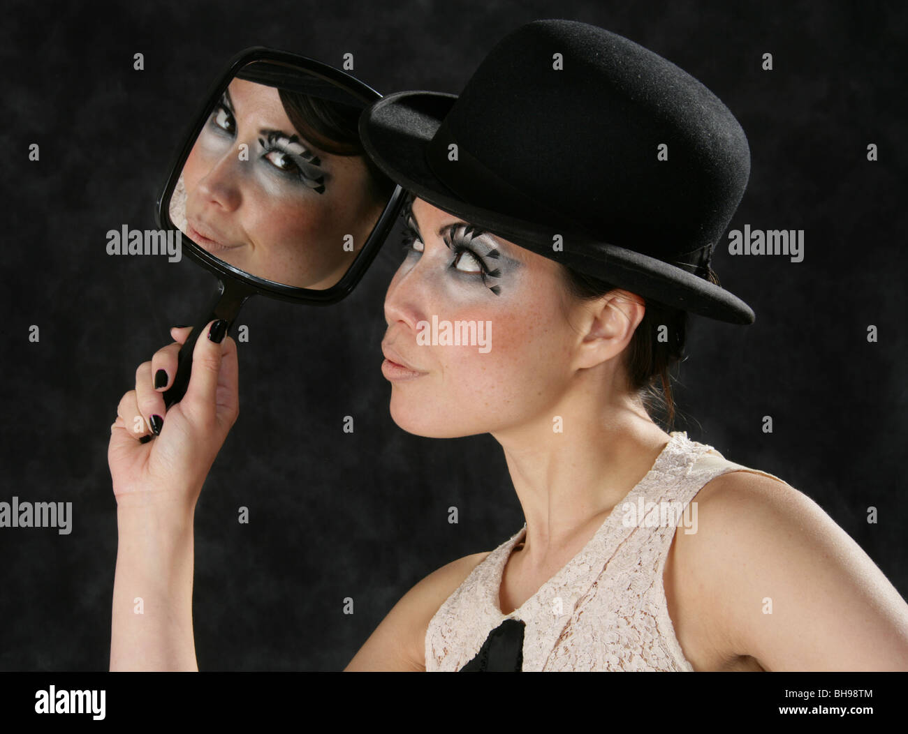 Giovane donna guardando il suo riflesso in uno specchio a mano Foto Stock