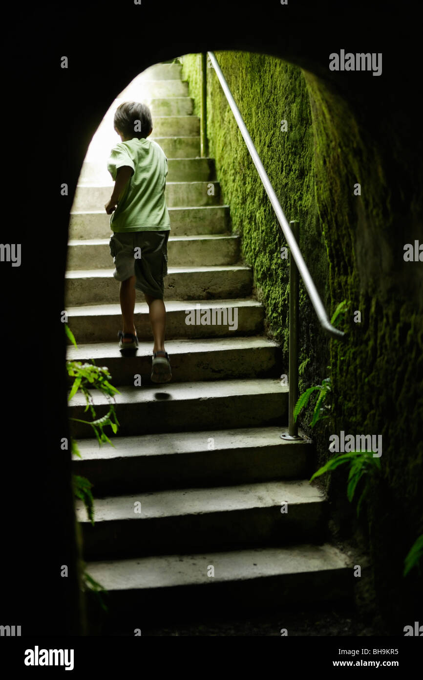 Ragazzo esegue le fasi fino alla fine del tunnel del giardino Foto Stock