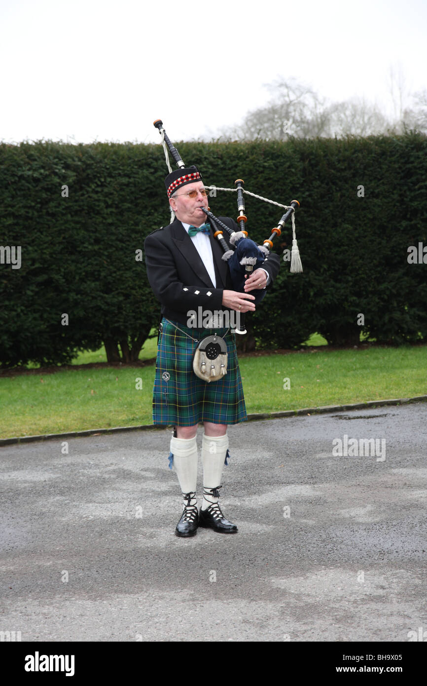 Un Highlands Piper riproduzione di cornamuse e indossando un tradizionale Kilt scozzese Foto Stock