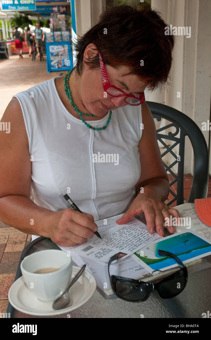 Donna scrivere cartoline in vacanza a Airlie Beach nel Queensland Foto Stock
