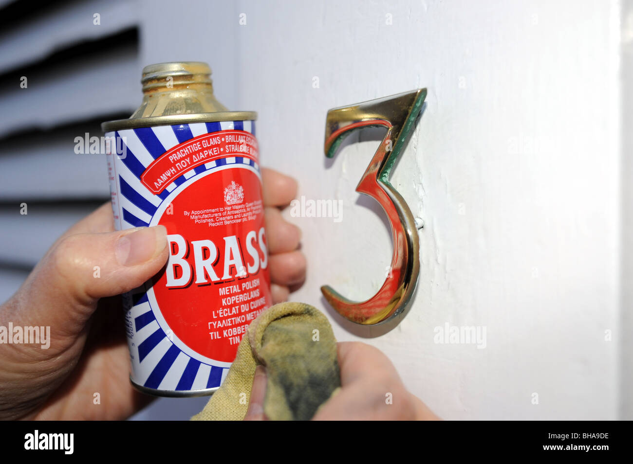 Ottone porta numero 3 essendo pulite con Brasso ottone polacco di metallo Foto Stock