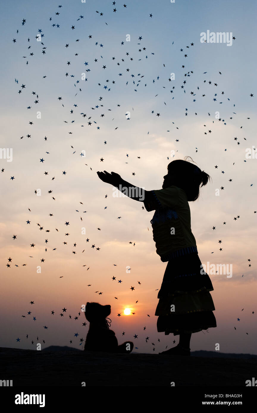 Silhouette di una giovane ragazza indiana la cattura di stelle cadenti al tramonto. India Foto Stock