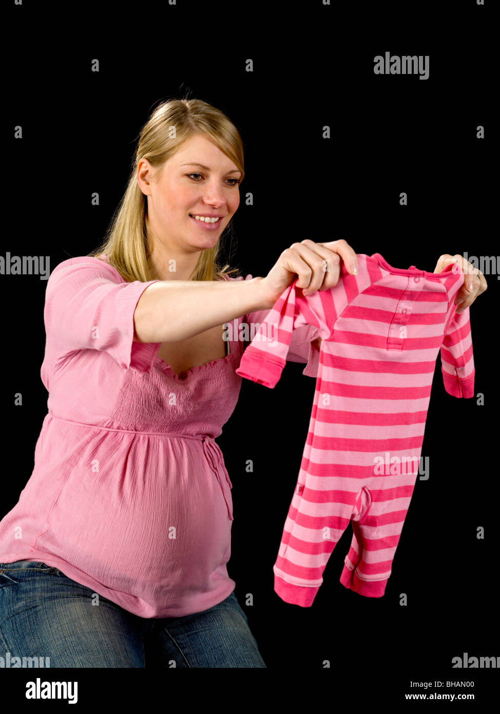 Donna incinta holding vestiti del bambino Foto Stock