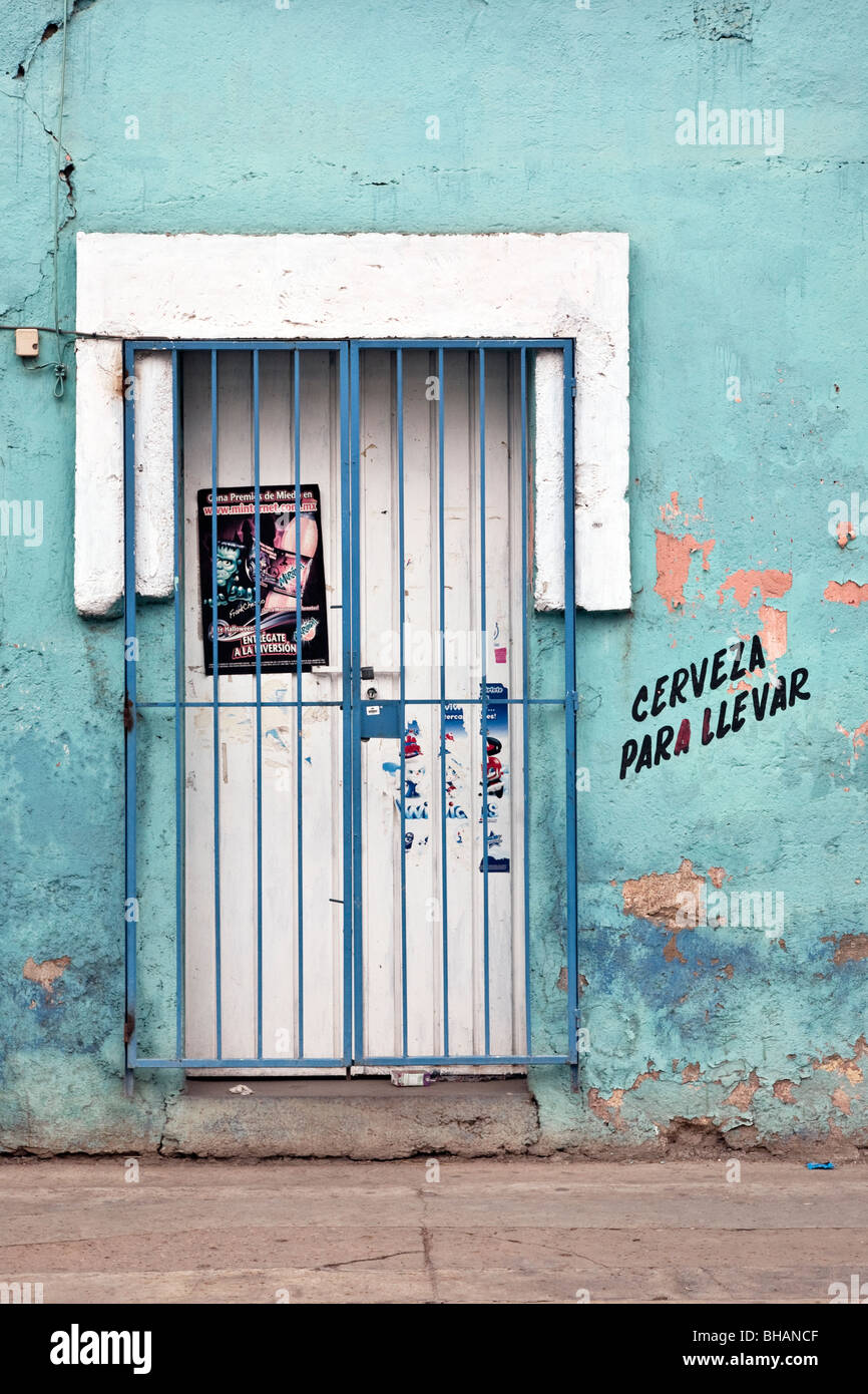 Chiusura porta sbarrata in bella acquamarina intonaco dipinto muro con  scritte di fading che offre birra a prendere fuori città di Oaxaca Foto  stock - Alamy