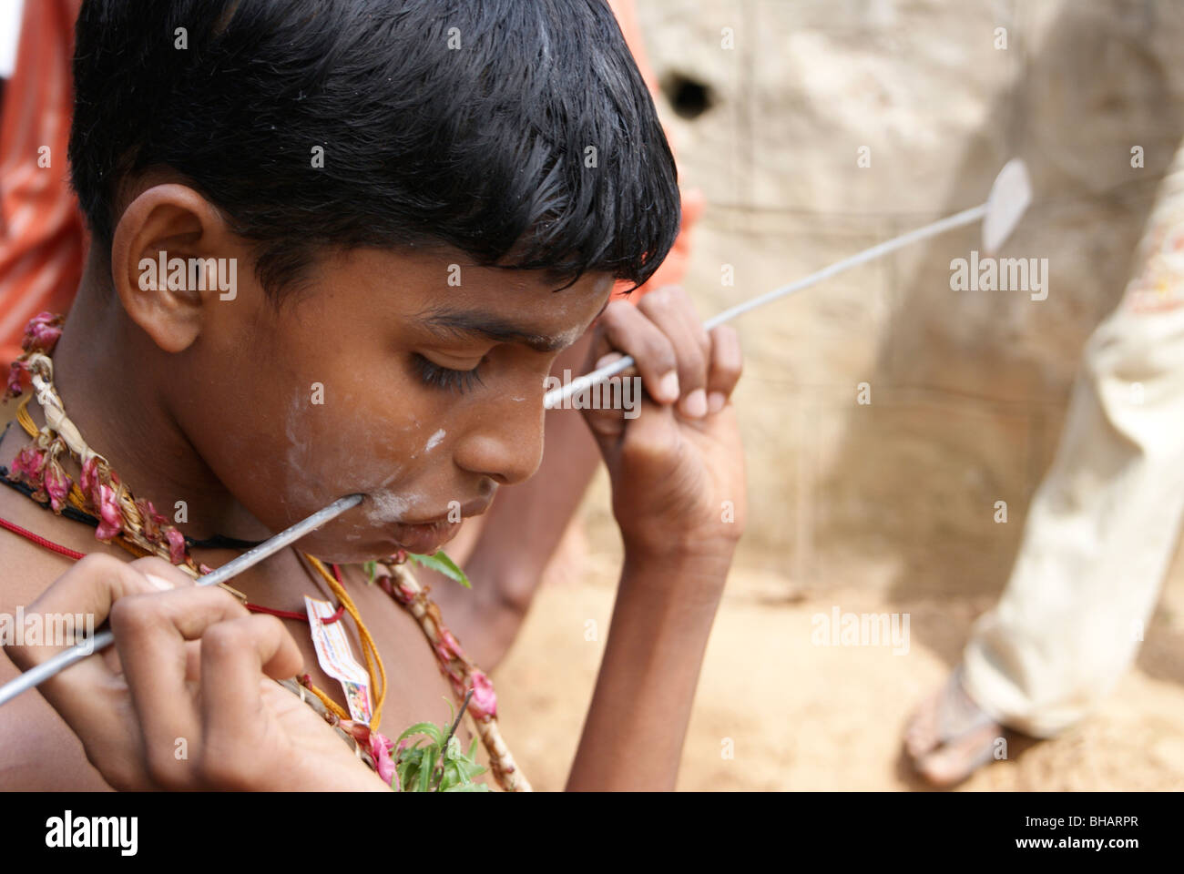 L'acciaio duro asta attraverso la guancia di un piccolo ragazzo, nel tempo di Kavadi (culto cerimoniale di Murugan ,i Tamil God of War ) Foto Stock