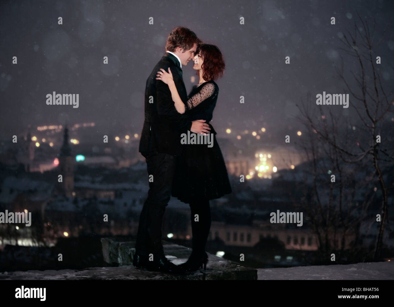 A piena lunghezza profilo di coppia romantica cercando in ogni altri occhi contro la città di notte per il giorno di san valentino Foto Stock