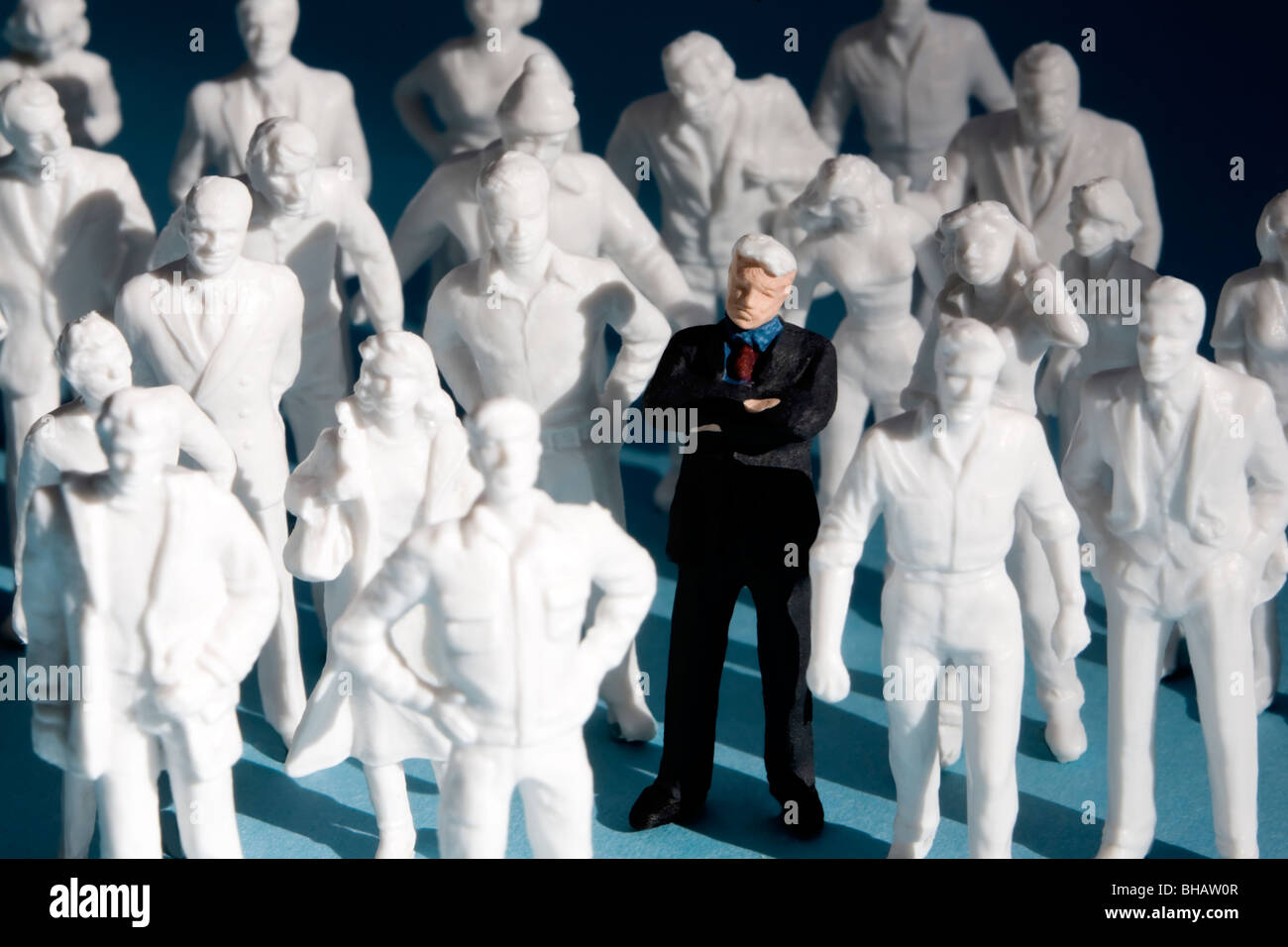 Miniatura figure di plastica, la folla di gente. Una figura è dipinta, circondato da bianco non verniciata figure. Foto Stock