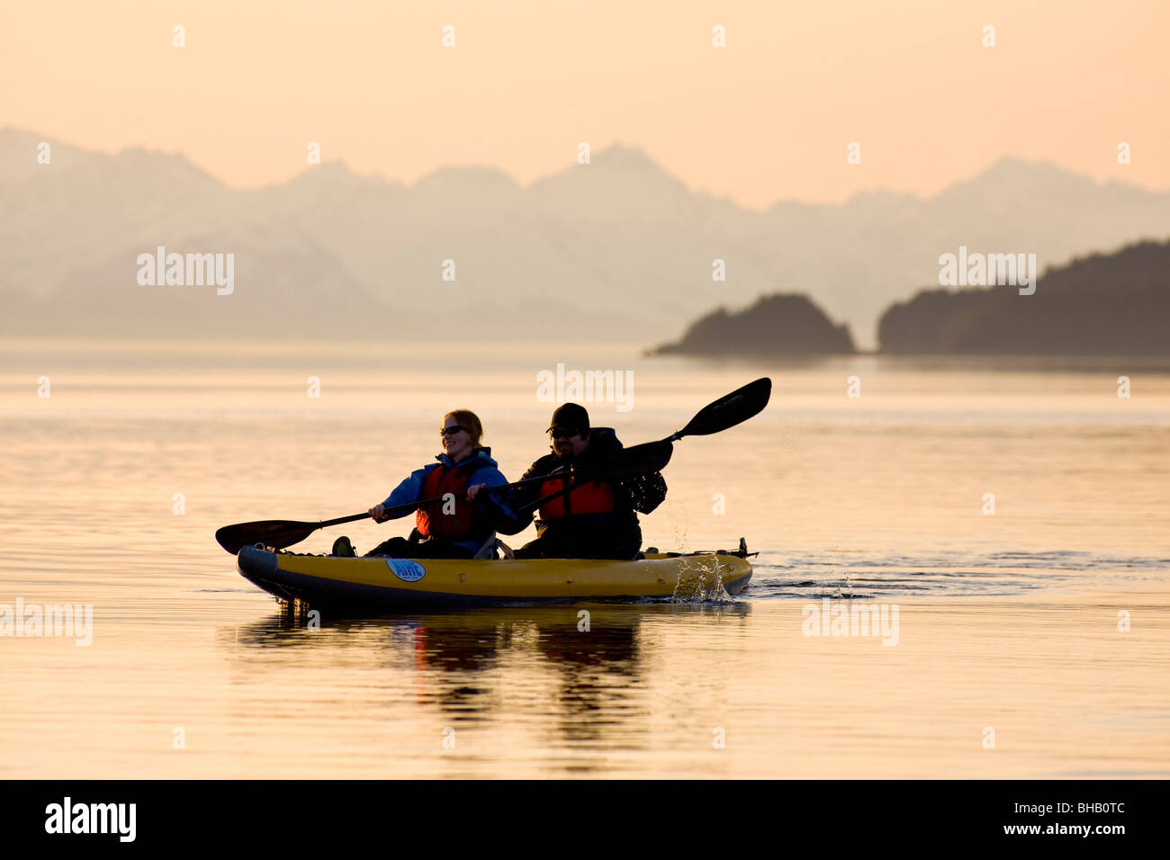 Sea Kayakers paddle il litorale al tramonto nel passaggio preferito vicino a Juneau in Alaska, Foto Stock