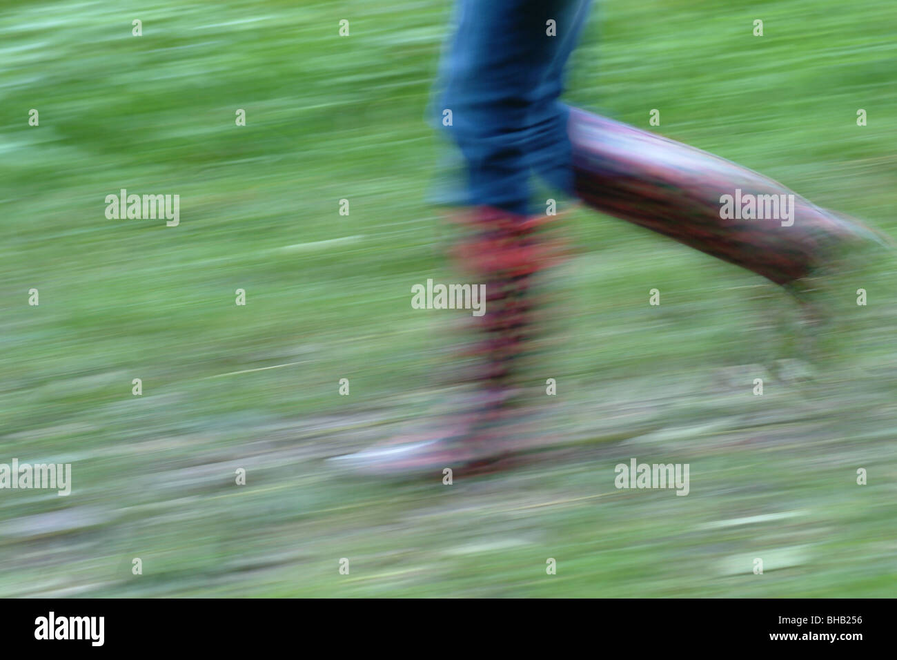 Giovane ragazza in jeans e rosso passeggiate wellingtons rapidamente causando la sfocatura in movimento. Regno Unito Foto Stock