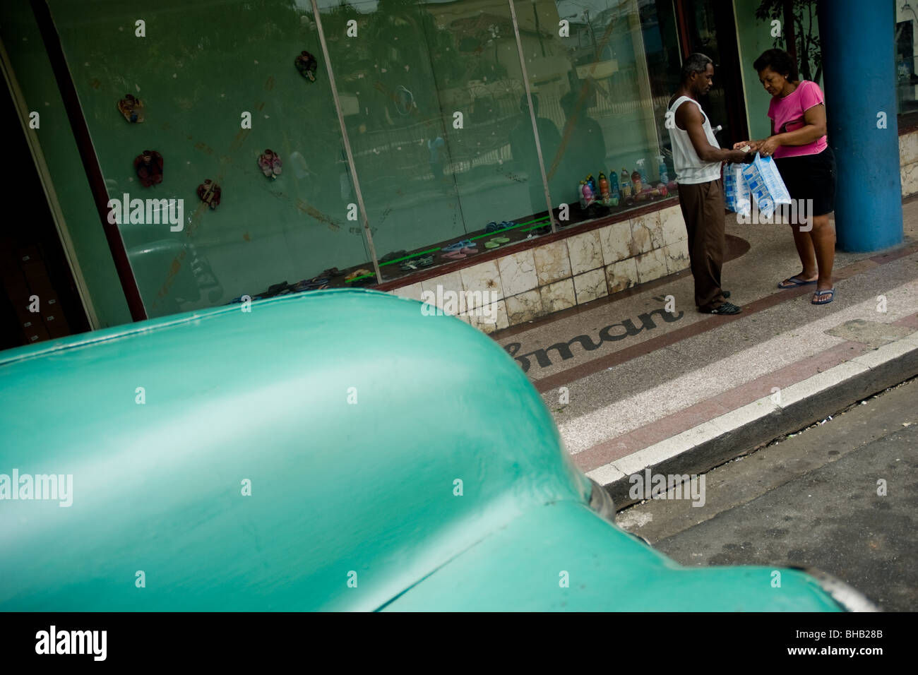 Un cubano matura la commutazione dei sacchetti di plastica nella parte anteriore di un vuoto che la finestra del negozio nel centro di Santiago de Cuba, Cuba. Foto Stock